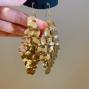 Detailed macro view of gold layered disc drop earrings with hammered metal texture