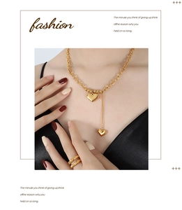 Detail of 18K gold-plated double heart necklace and textured ring on black silk outfit