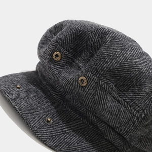 Detailed close-up of dark grey herringbone wool texture and vintage bronze side button