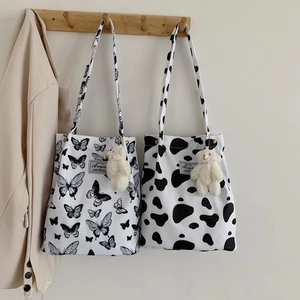 Detail of canvas tote bags with butterfly and cow prints featuring plush bear charms