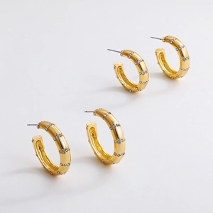 Vue macro des boucles d'oreilles C en or 18K avec diamants fins et finition polie