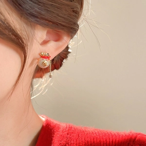 Détail de la boucle d'oreille à pampilles avec sac porte-bonheur et chaîne en or
