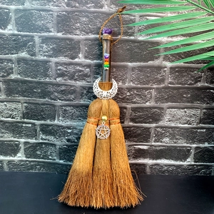 Detail of wooden witch broom with purple amethyst, chakra stones, and crescent moon