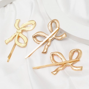 Three elegant gold and beige enamel bow hair clips on white silk background