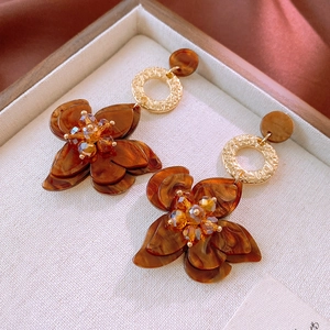 Detail von bernsteinfarbenen Harzblumenohrringen mit Kristallstaubblatt und Retro-Design