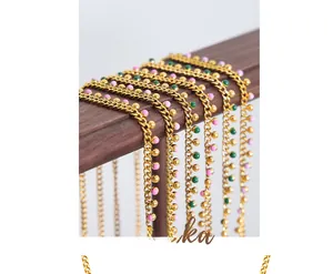 Close-up of gold tassel necklaces with pink and green beads on a wooden display stand