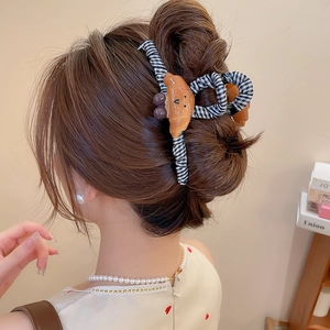 Détail d'une pince à cheveux à carreaux avec un décor de croissant sur les cheveux