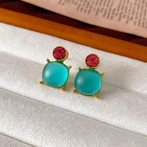 Macro shot of vintage style earrings with rose pink crystal and teal matte square gems