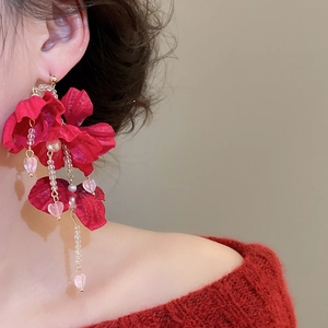 Macro detail of red fabric flower earrings with crystal heart and pearl tassel strands