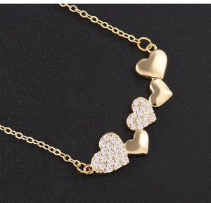 Detail of linked heart necklace pendant featuring cubic zirconia pavé and gold finish