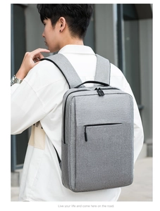 Modern grey backpack for men and women shown on model with minimalist urban architecture