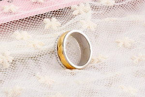 Macro shot of two-tone stainless steel ring with diamond-set edge and geometric facets