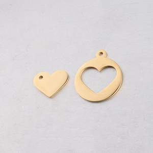 Macro detail of gold stainless steel heart pendant and circular hollow heart charm