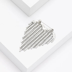 Detail of silver tassel brooch with rhinestone chains on a white geometric background