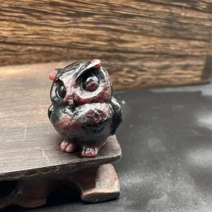 Macro detail of hand-carved natural stone owl figurine on a rustic wooden base