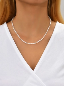 Close-up of irregular baroque pearl necklace with gold bead accents on a model