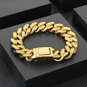 Detail of heavy golden Cuban link bracelet with square clasp on black pedestal