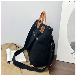Detail view of large canvas tote bag with brown leather handles and side text print