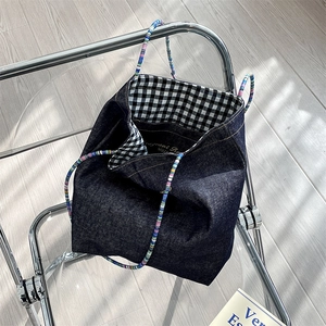 Detailed macro view of denim tote bag featuring gingham lining and colorful handles