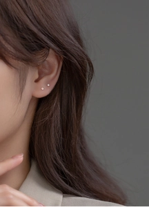 Macro shot of 999 silver four-prong crystal and pearl minimalist studs on ear