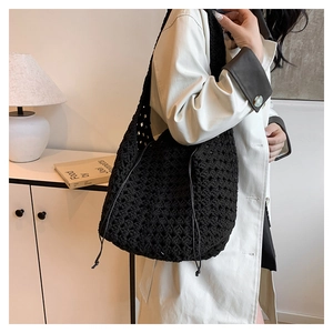 Dettaglio della borsa in maglia nera traforata con coulisse indossata con un trench