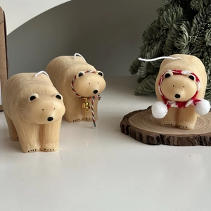 Detailed view of polar bear candles with festive scarves on a wooden base with pine needles