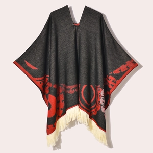 Red and black patterned women's winter poncho shawl with cream fringe tassels on white background