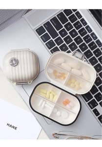 Detail shot of mini suitcase-shaped pill box with transparent dividers on a laptop keyboard