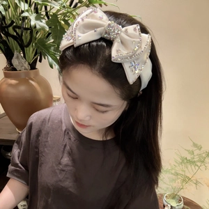 Beige wide rhinestone headband with crystal bow designs shown on a model