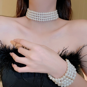 Close-up of elegant four-layer white pearl choker and matching wide cuff bracelet set