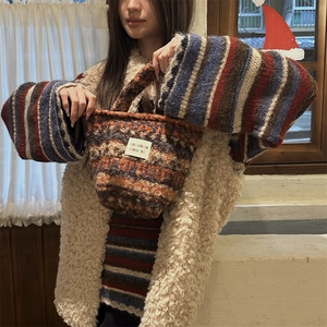 Close-up of a chunky knit bucket bag featuring a colorful geometric woven pattern and handle