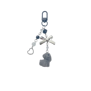 Cute plush puppy keychain with silver bow, black dice, and metal heart on a matte carabiner