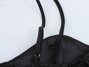 Close-up of adjustable straps and satin fabric detail on a black cocktail dress
