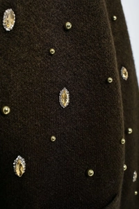Detail of dark brown knit fabric with gold beads and amber rhinestones for cardigans