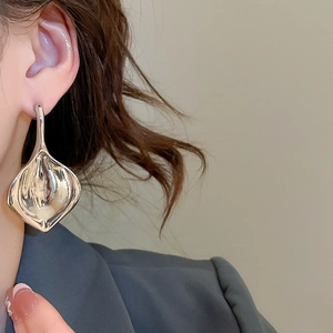 Primo piano di un orecchino geometrico astratto in argento indossato da una modella
