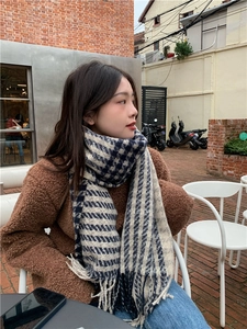 Navy and beige houndstooth scarf with tassels styled in a cozy cafe setting