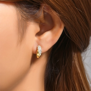 Detail of twisted gold earring with micro-paved crystals worn on a female model's ear