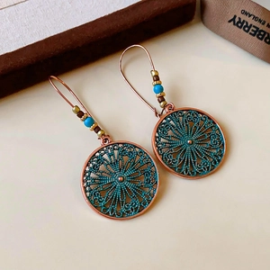 Close-up of vintage bohemian flower drop earrings with turquoise beads and bronze finish