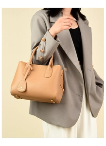 Detail of light brown lychee grain leather handbag with gold protective bottom studs