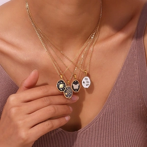 Detail shot of four gold 18K plated necklaces with diverse vintage oval pendants on a model