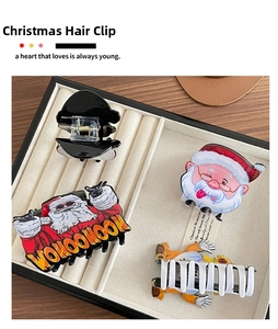 Detailed view of colorful acrylic Christmas Santa hair claws on a beige velvet jewelry tray