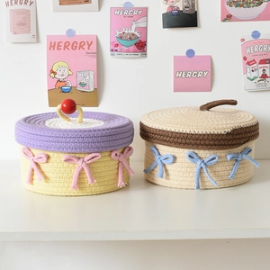 Close-up of handmade woven cotton rope storage baskets with lids and decorative bows