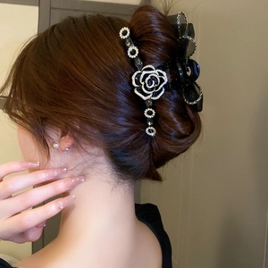 Détail de pince à cheveux avec nœud en maille noire, camélia et strass brillants