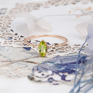 Macro view of marquise-cut olive green gemstone ring with rose gold wavy band details