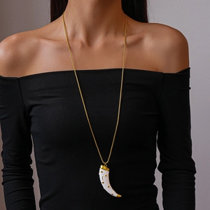 Detail of a vintage horn pendant necklace with gold chain on a black outfit