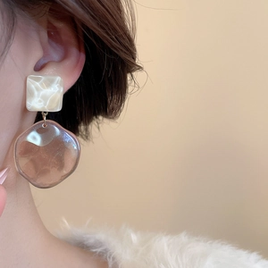 Close-up of model wearing resin irregular geometric earrings in cream and amber brown