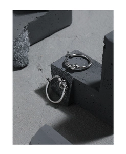 Macro shot of S925 hallmark on silver knot earrings placed on gray concrete blocks