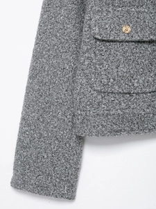 Detailed macro shot of grey textured boucle fabric jacket with decorative gold buttons