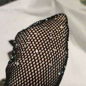 Detailed macro view of black fishnet leggings fabric with sparkling rhinestone embellishments