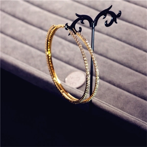 Macro detail of large gold-tone crystal hoop earrings with a size reference coin